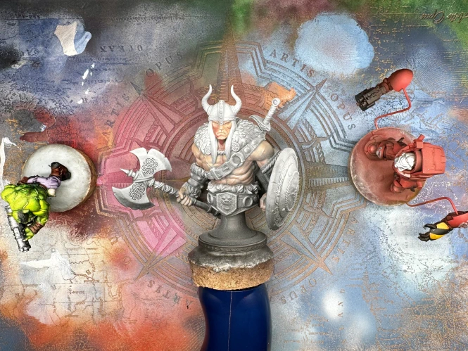 A shot from above of three minis sitting on a colourful paint-covered texture palette.