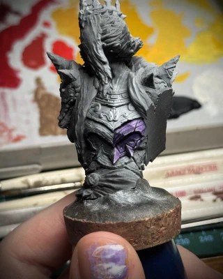 A spooky lady, zenithal primed to highlight light volumes. One of the armour panels is being painted in various shades of purple, the stark changes of contrast aiming for a non-metallic-metal effect.