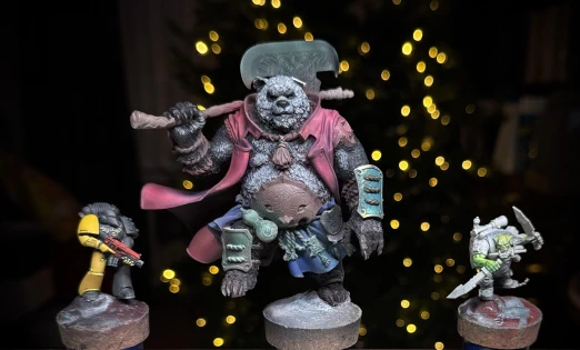 Three miniatures in various early stages of being painted  (and repaired). A little half-yellow guy, a little partly-green guy, and one great big guy missing a left ear. Festive background lights though, so all is well.