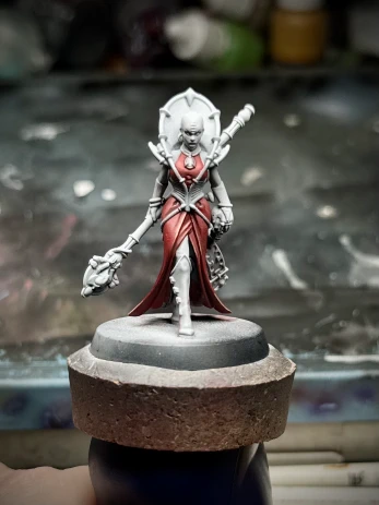 A front shot of a charming bald lady (definitely not a bug), mainly still zenithal primer but with a fancy frock that may or may not read as red.