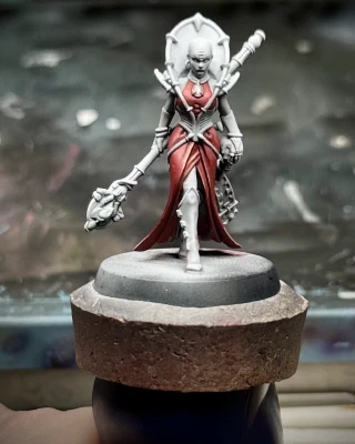 A front shot of a charming bald lady (definitely not a bug), mainly still zenithal primer but with a fancy frock that may or may not read as red.
