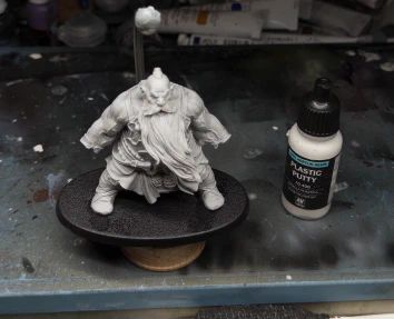 A whole new child appears! Bearded and girthy! Its absurd size in comparison with gaming minis is subtly hinted at by both cramming it inside the largest Rathcore painting handle, tacked to a painting base probably intended for horses*, and standing it next to an industry-standard reference pot of Vallejo plastic putty.

*🤷‍♂️