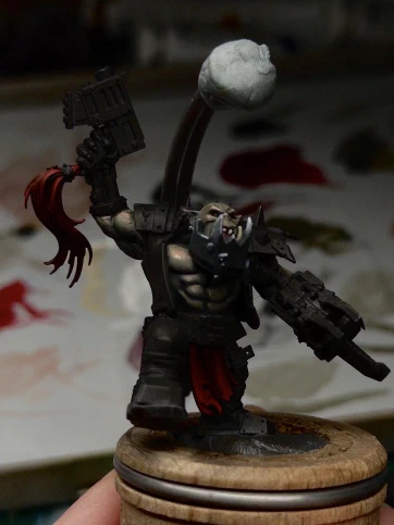 Little tip-taps of light greys added to the metallic jaw, some bone colour to the teefs, and initial layers of dark desaturated red in the shadows of gun-hairdo and loincloth up to full Mephiston Red as the extreme highlight.