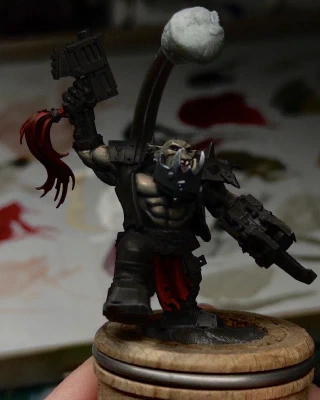 Little tip-taps of light greys added to the metallic jaw, some bone colour to the teefs, and initial layers of dark desaturated red in the shadows of gun-hairdo and loincloth up to full Mephiston Red as the extreme highlight.