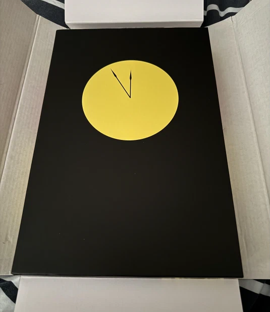 The freshly-unpacked jet black sleeve box of Absolute Watchmen with its bright yellow clock face.