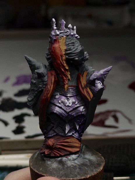 A Spooky Lady recap! This is a miniature display bust of a veiled and crowned undead lady in heavy spiked armour. Only two sets of colours are currently in use: the armour is picked out in purples and pinks while her veil, scarf and sash share the same red tones. Extreme highlights are placed to suggest that the purple surfaces are ‘shiny’. A small cast shadow from one of the spikes has been painted over the scarf to help imply directional light.
